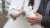 bruidspaar met koppel witte duiven in handen